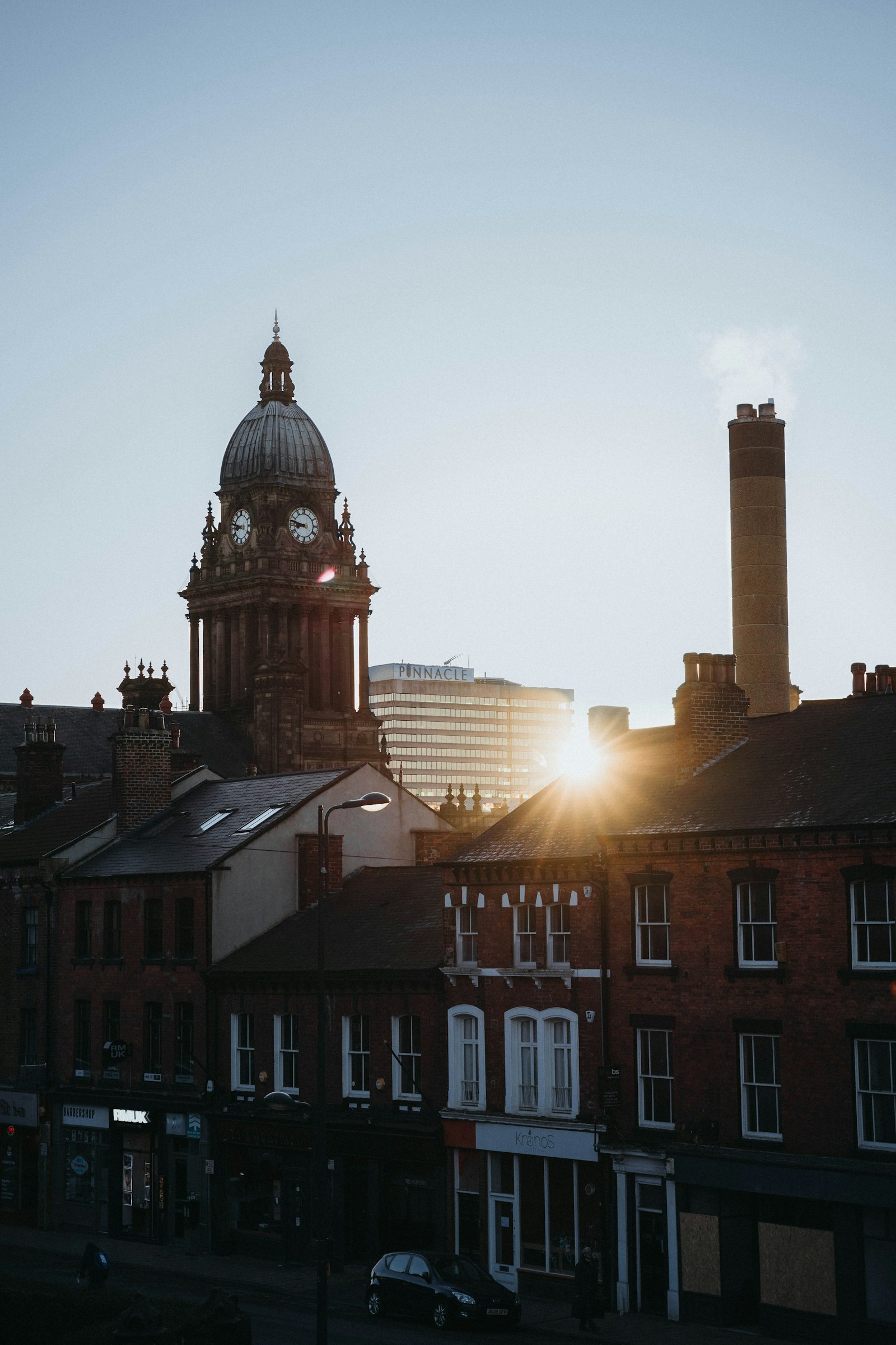 Leeds Town Hall clock tower at golden hour, with the Pinnacle building in the background and red brick Victorian buildings in the foreground