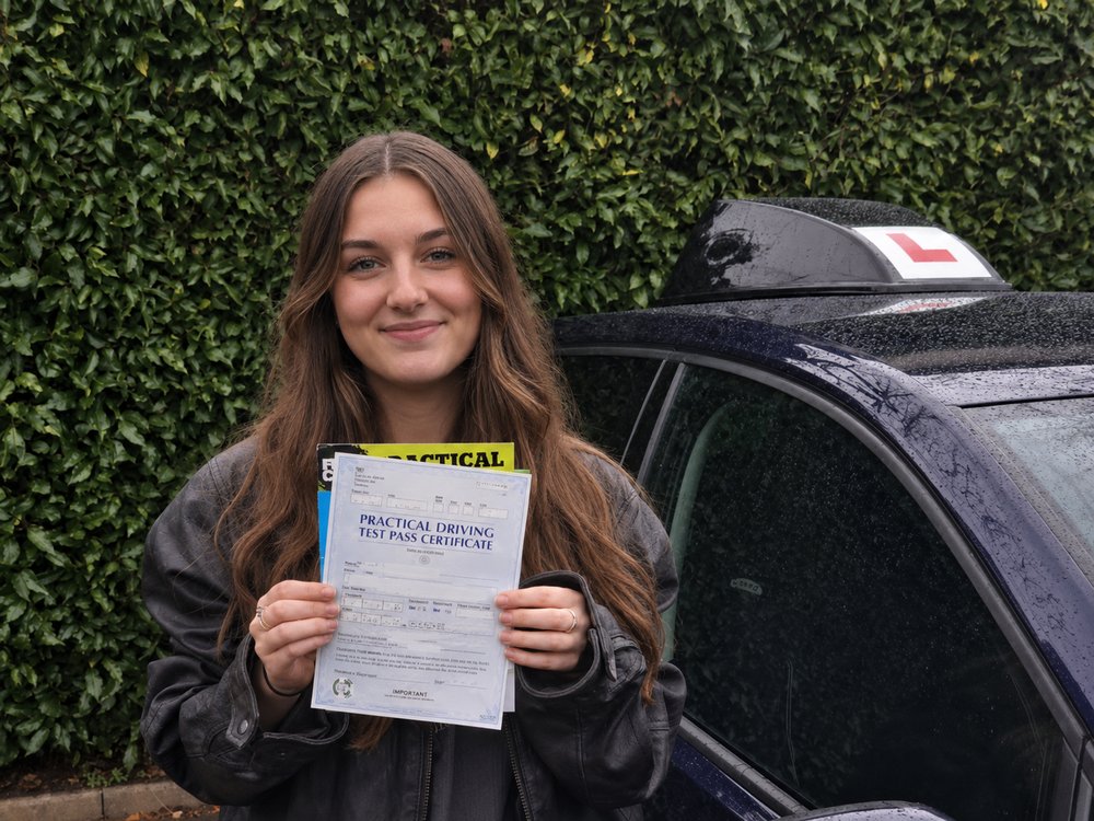 Amelie holding her pass certificate after passing her UK driving test