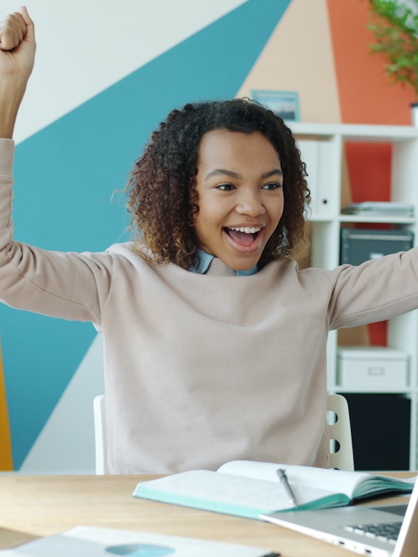 A learner celebrating with arms raised